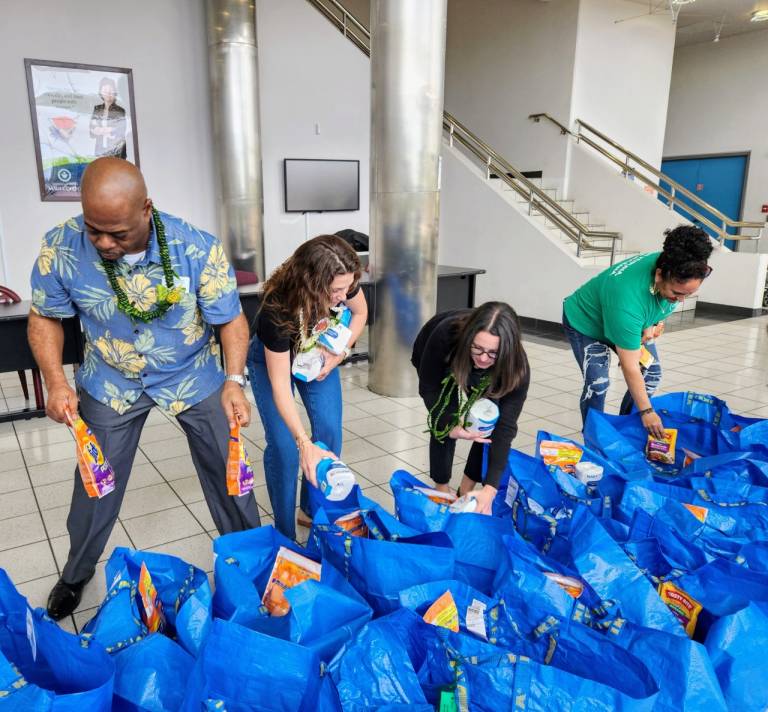 several people fill blue bags with groceries